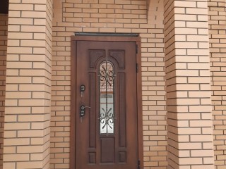 Входная дверь в частный дом со стеклом и ковкой